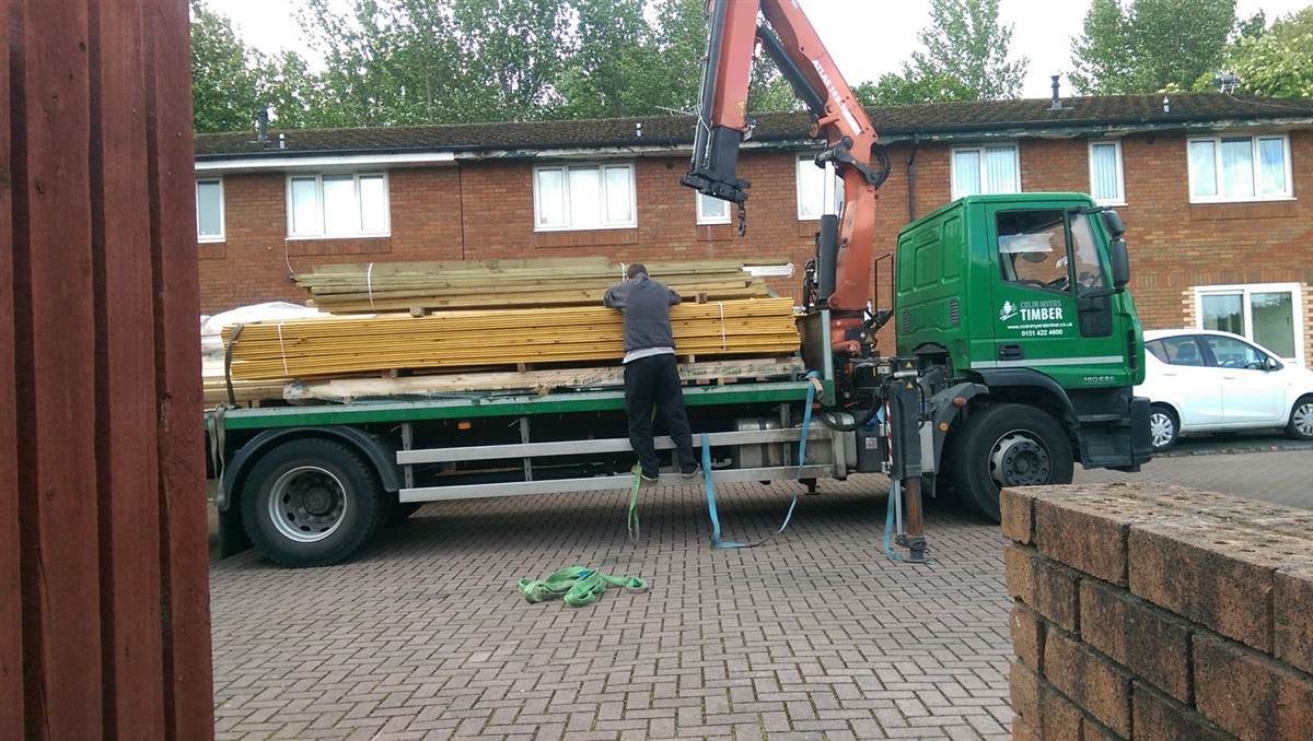 Timber delivery arriving by crane lorry — a full deck's worth of treated timber