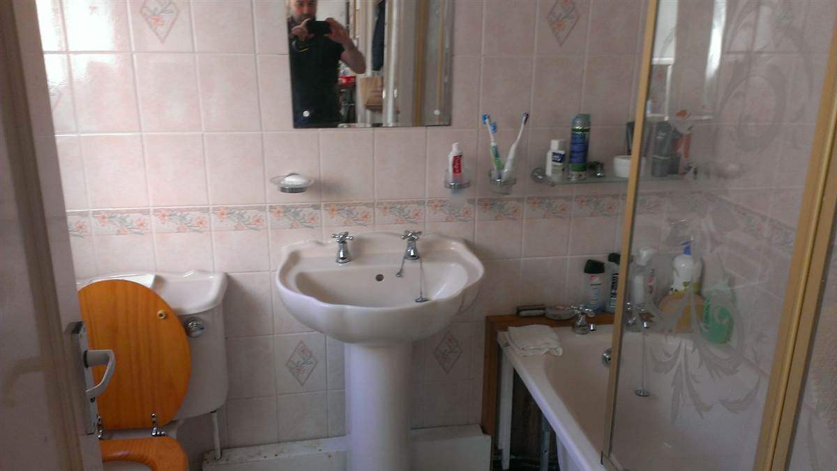 The original bathroom before conversion — standard bath, pink tiles, raised toilet seat