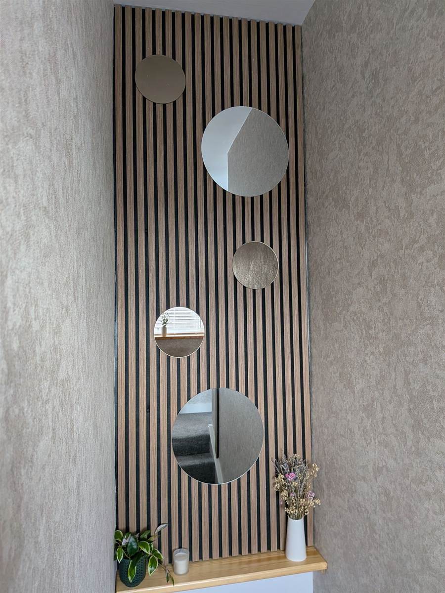 After — finished stairwell with oak slat panel, four circular mirrors and a shelf below