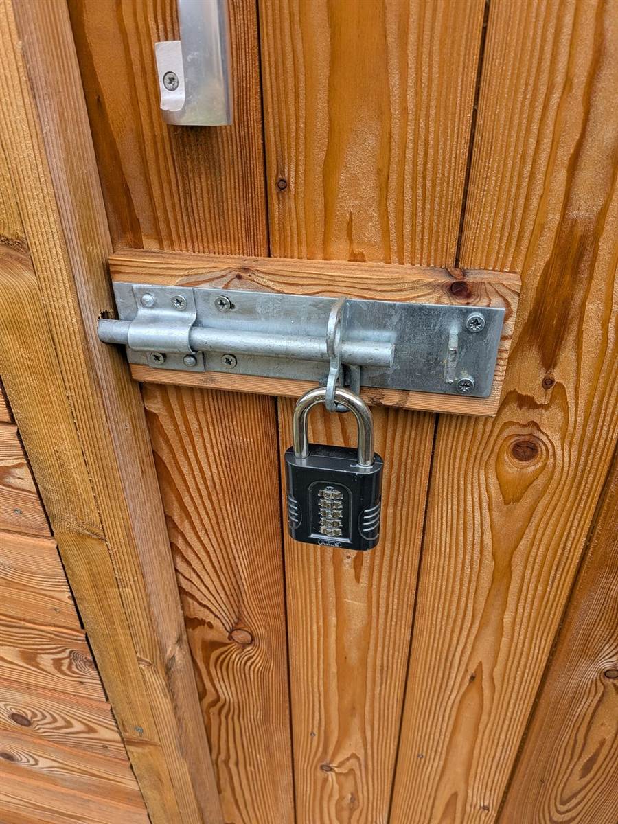 A heavy-duty hasp and combination padlock fitted to a shed door — simple, solid security