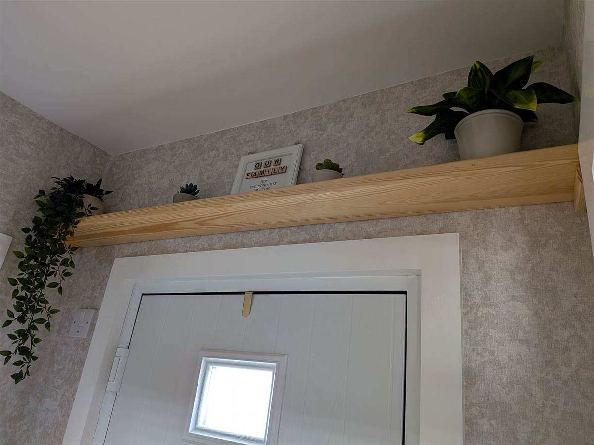 A solid timber shelf, fixed securely above a doorway — strong enough to actually use